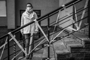 Photo of a girl in a mask. Standing on the street with danger warning tapes.