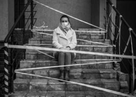 foto de una chica con una máscara. sentado en la calle con cintas de advertencia de peligro.