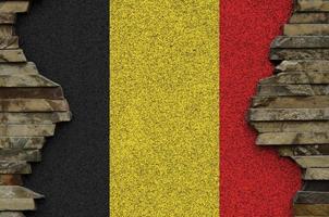 Belgium flag depicted in paint colors on old stone wall closeup. Textured banner on rock wall background photo