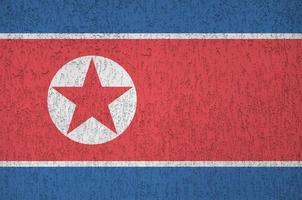 North Korea flag depicted in bright paint colors on old relief plastering wall. Textured banner on rough background photo