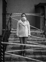 Photo of a girl in a mask. Standing on the street with danger warning tapes.