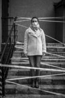 Photo of a girl in a mask. Standing on the street with danger warning tapes.