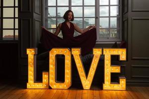 Women with closed eyes in red dress behind letters LOVE photo