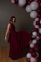 Women in red dress and high heels stepping on balloon photo