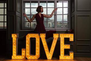 Women with hands in air in red dress behind letters LOVE photo