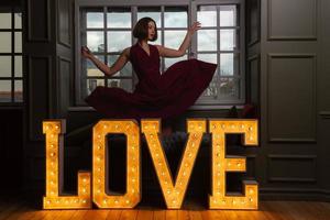 Women with hands in air in a falling red dress behind letters LOVE photo