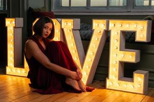 Woman in red dress sitting in front of LOVE letters photo