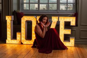 mujer con vestido rojo haciendo la letra v con las manos frente a cartas de amor foto