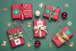 Handmade wrapped red, green gift boxes decorated with ribbons, snowflakes and numbers, Christmas decorations and decor on green table Xmas advent calendar concept Top view Flat lay Holiday card photo