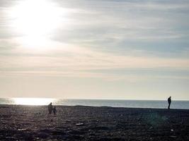 People on the spring pebble beach at sunset. Vacation on the beach. Rest on the sea. Rocky shore. photo