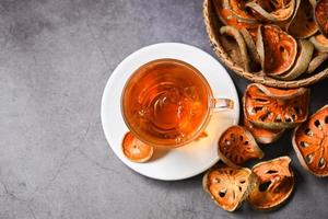 Bael tea on glass with dried bael slices on dark background, Bael  juice - Dry bael fruit tea for health - Aegle marmelos - top view photo