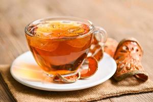 Bael tea on glass with dried bael slices on wooden background, Bael  juice - Dry bael fruit tea for health - Aegle marmelos photo