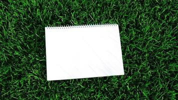 Empty white paper on green grass background. For message flat lay with copy space for text or products presentation. Nature concept, business and lifestyle environment. photo