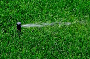 Automatic garden irrigation system watering lawn. Savings of water from sprinkler irrigation system with adjustable head. Automation for lawn irrigation, gardening, soccer fields or golf courses. photo