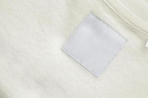 Blank white laundry care clothes label on fabric texture background photo