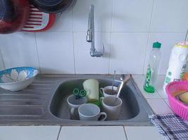 Dirty dishes and glasses in the sink that have not been washed. Piles of dirty dishes and glasses that haven't been washed, real life at the end of the year photo