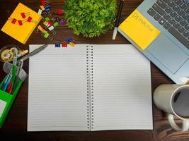 endecha plana, papel simulado. espacio de trabajo en el fondo del escritorio de la oficina desde la vista superior. con papel blanco en blanco, computadoras portátiles, útiles de oficina, lápices, hojas verdes y tazas de café en una mesa de madera. foto