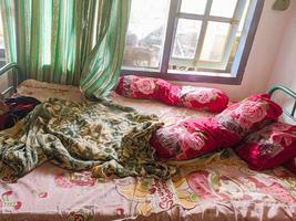 The bedroom is a mess. A child's room with a messy bed and pillows, bolsters and quilts that have not been tidied up. real life. photo