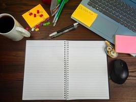 endecha plana, una maqueta de un cuaderno. espacio de trabajo en el fondo del escritorio de la oficina desde la vista superior. con cuadernos blancos, portátiles, útiles de oficina, lápices y tazas de café en el escritorio de madera. foto