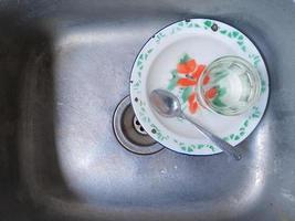 Dirty dishes and glasses in the sink that have not been washed. Piles of dirty dishes and glasses that haven't been washed, real life at the end of the year photo