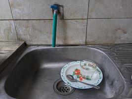 platos y vasos sucios en el fregadero que no han sido lavados. montones de platos sucios y vasos que no han sido lavados, la vida real al final del año foto