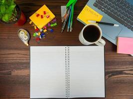 Flat lay, a mock up of a notebook. workspace in the background of the office desk from the top view. with white notebooks, laptops, office supplies, pencils, and coffee cups in the  wooden desk. photo