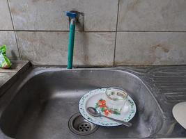 Dirty dishes and glasses in the sink that have not been washed. Piles of dirty dishes and glasses that haven't been washed, real life at the end of the year photo