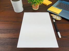 Flat lay, mock up paper. workspace in the background of the office desk from the top view. with blank white paper, laptops, office supplies, pencils, green leaves, and coffee cups photo