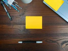 Flat lay, mock up yellow notes. workspace in the background of the office desk from the top view. with yellow notes, laptops, office supplies, pencils, and coffee cups in the wooden table. photo