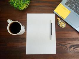 Flat lay, mock up paper. workspace in the background of the office desk from the top view. with blank white paper, laptops, office supplies, pencils, green leaves, and coffee cups photo