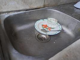 platos y vasos sucios en el fregadero que no han sido lavados. montones de platos sucios y vasos que no han sido lavados, la vida real al final del año foto