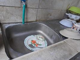 platos y vasos sucios en el fregadero que no han sido lavados. montones de platos sucios y vasos que no han sido lavados, la vida real al final del año foto