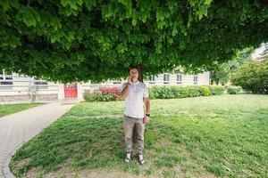 Funny man stand under tree and speaking on phone. photo