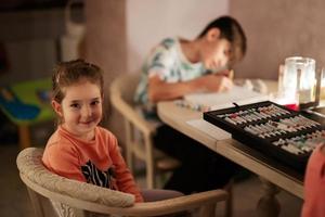 Family spending time together during an energy crisis in Europe causing blackouts. Kids drawing in blackout. photo