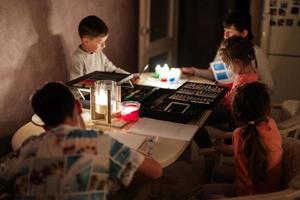 Family spending time together during an energy crisis in Europe causing blackouts. Kids drawing in blackout. photo