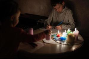 Family spending time together during an energy crisis in Europe causing blackouts. Kids drawing in blackout. photo