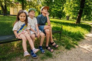 Three kids sitting in bench at park. Two brothers and sister. photo