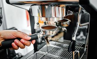 Close-up of hand barista making fresh coffee process of preparing coffee tablet before installing it into the coffee machine photo