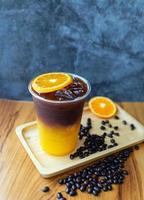 menú de bebida de café helado fusión de naranja americano con fruta fresca de naranja mezclada en una taza de plástico, producto de menú de bebida. foto