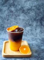 menú de bebida de café helado fusión de naranja americano con fruta fresca de naranja mezclada en una taza de plástico, producto de menú de bebida. foto