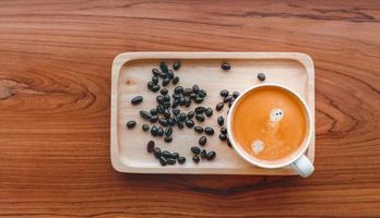 White cup of espresso coffee and Roasted coffee beans on a wooden tray photo