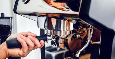 Close-up of hand barista making fresh coffee process of preparing coffee tablet before installing it into the coffee machine photo