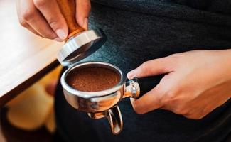 Close-up of hand Barista cafe making coffee with manual presses ground coffee using tamper at the coffee shop photo