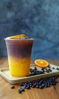 menú de bebida de café helado fusión de naranja americano con fruta fresca de naranja mezclada en una taza de plástico, producto de menú de bebida. foto