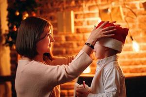 Mother puts Santa Claus Christmas hat on child. photo