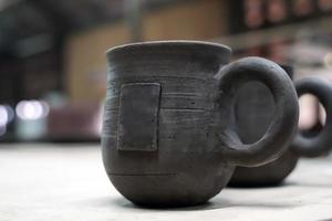 coffee mug with handle. The sculptor has already formed and prepared to lead to the incineration process. Soft and selective focus. photo