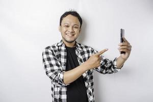 A portrait of a happy Asian man is smiling while holding on his phone, isolated by white background photo