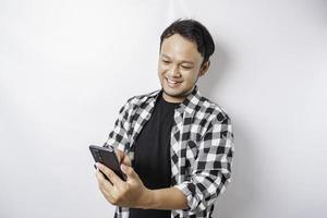 un retrato de un hombre asiático feliz sonríe mientras sostiene su teléfono, aislado por fondo blanco foto