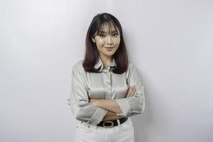 Portrait of a confident smiling Asian woman wearing sage green shirt standing with arms folded and looking at the camera isolated over white background photo