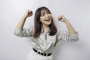 A young Asian woman with a happy successful expression wearing sage green shirt isolated by white background photo